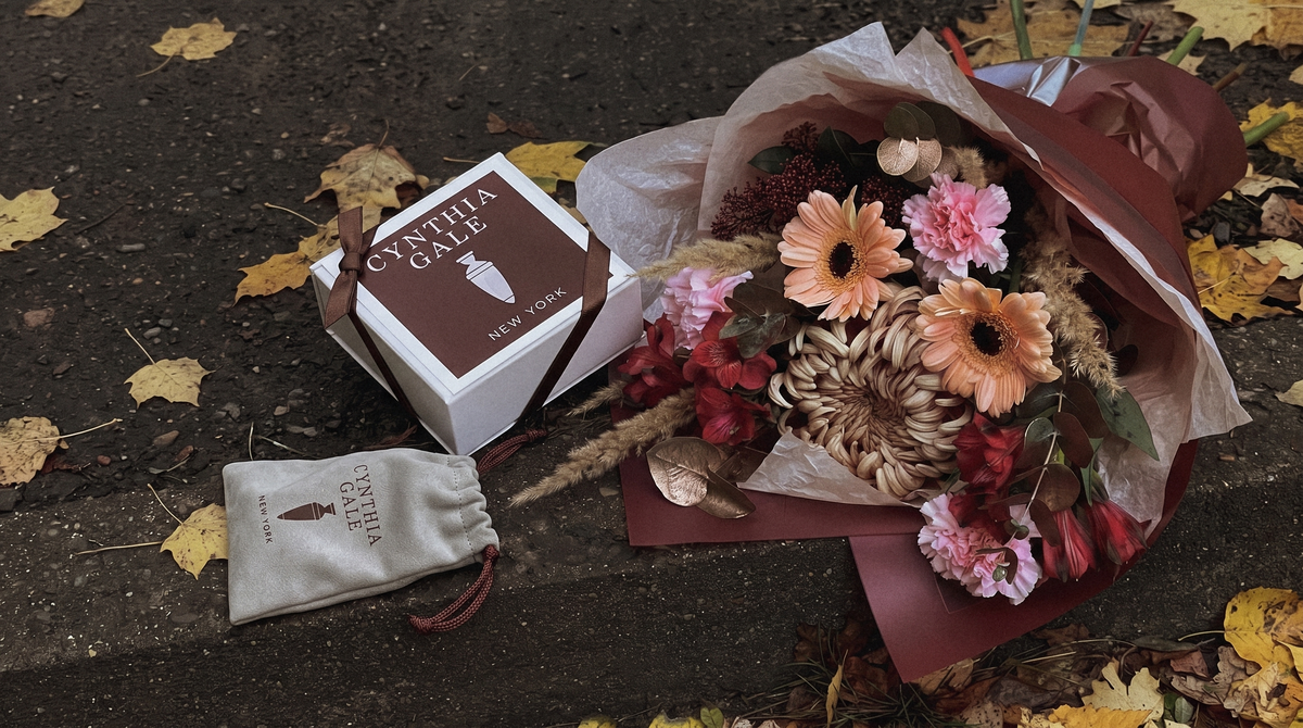 Cynthia Gale New York gift box and grey suede jewelry pouch with an autumn bouquet on a city curb